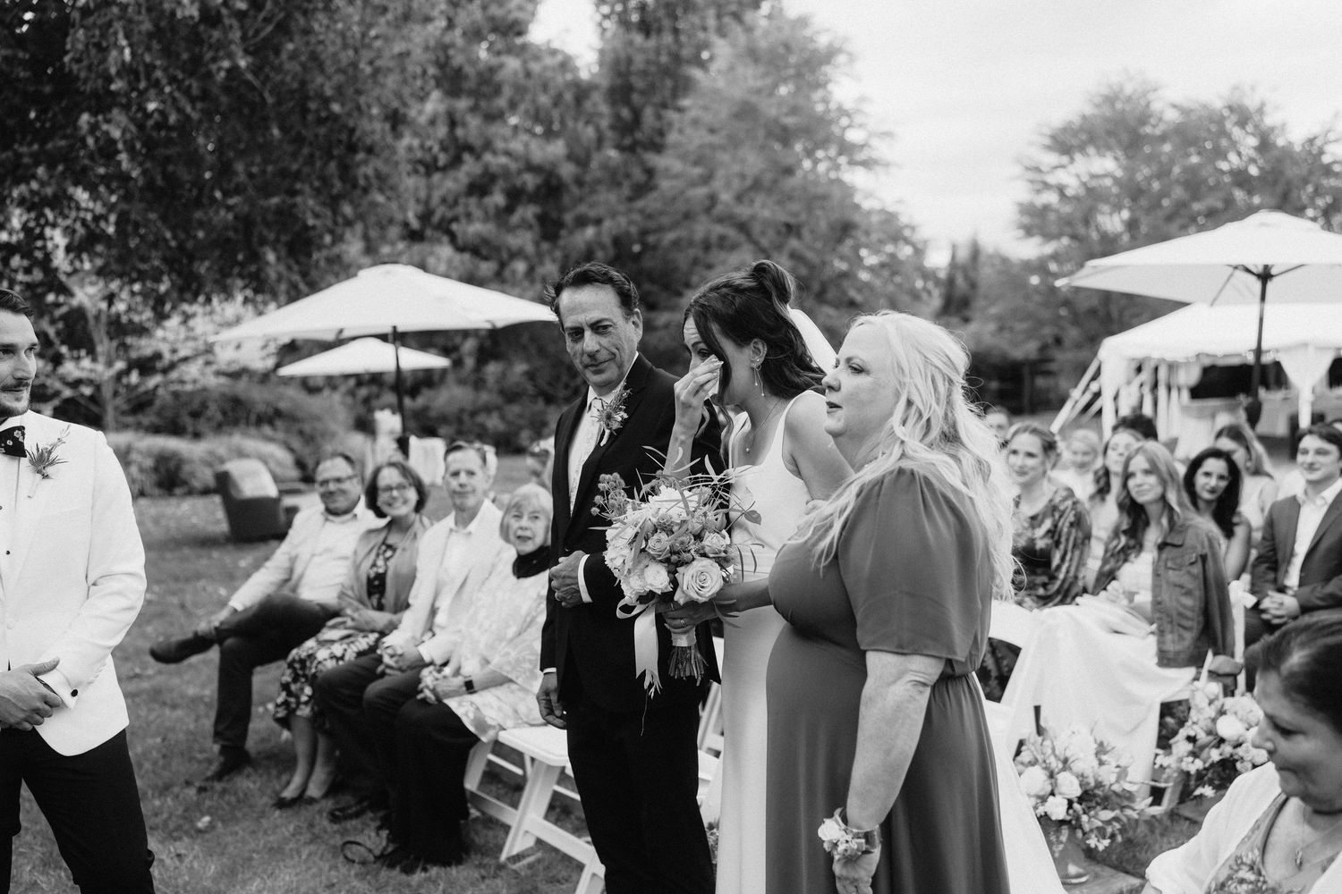 Black and white photo of guests mingling at an outdoor wedding reception.