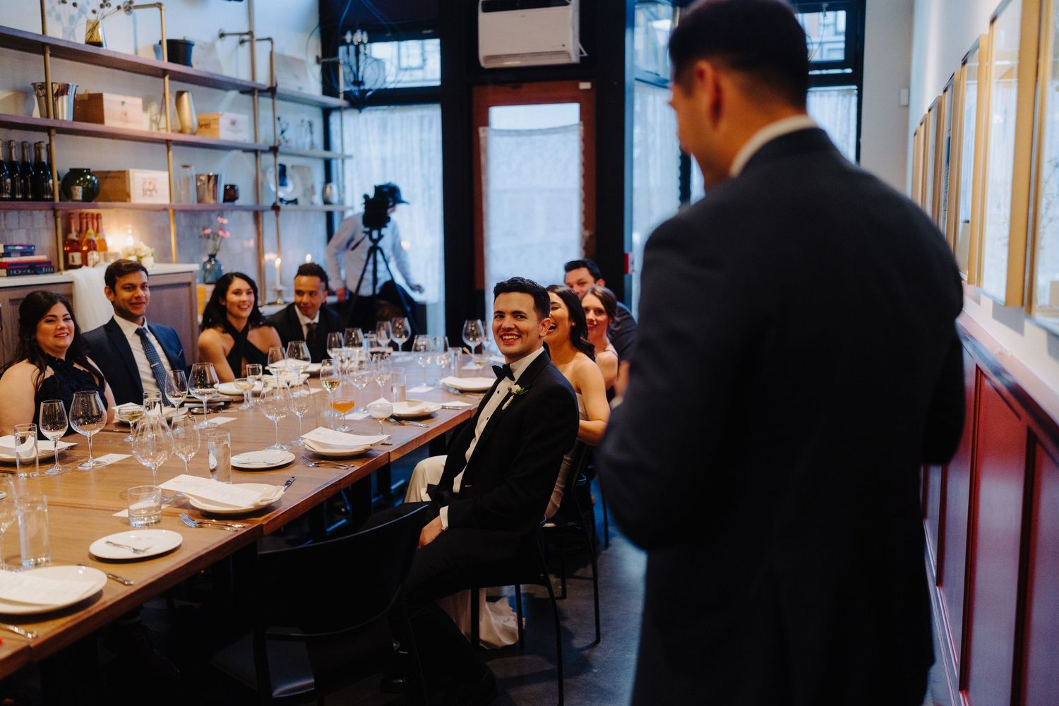 Wedding reception guests seated at a long dining table in an intimate restaurant setting.
