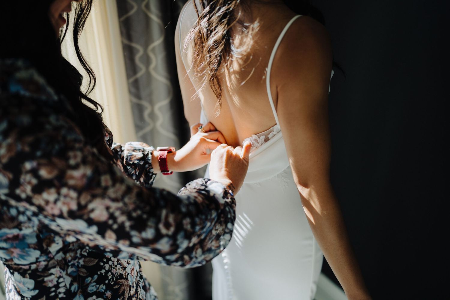 A close-up detail shot of someone in a white dress holding a small glass.
