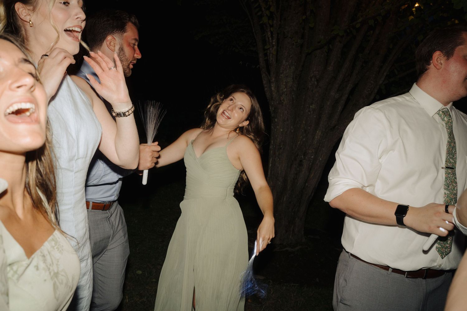 Wedding reception guests dancing and celebrating at a nighttime party.