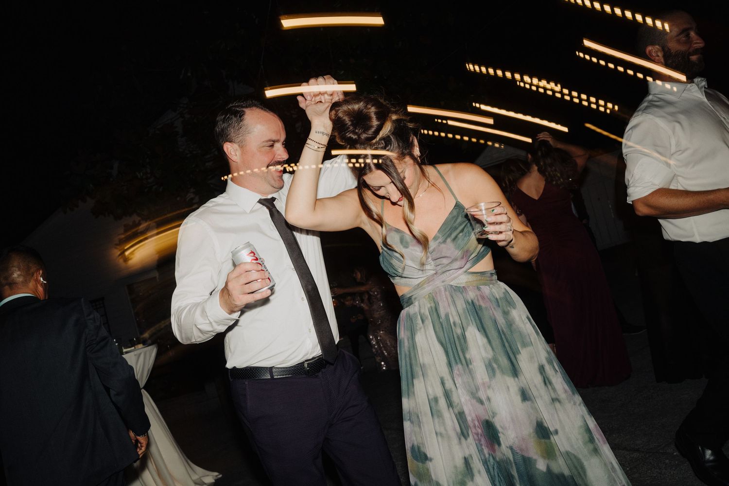 Candid nighttime reception photo with string lights creating warm ambiance overhead.