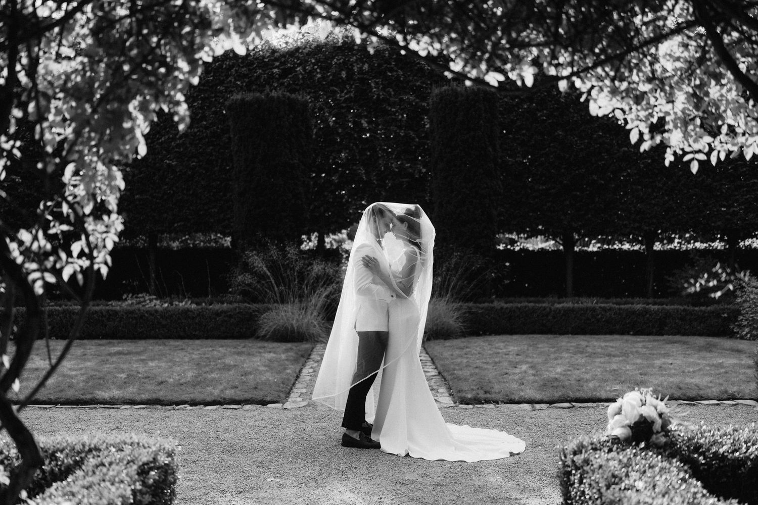 Black and white wedding photography capturing intimate moments in an outdoor garden setting.