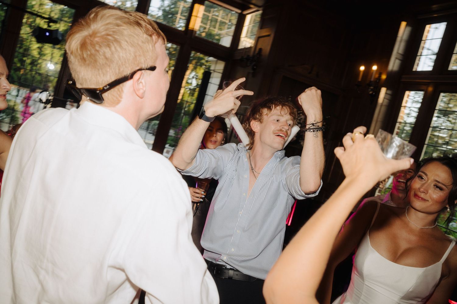 Wedding party celebrates with dancing and laughter at indoor reception.