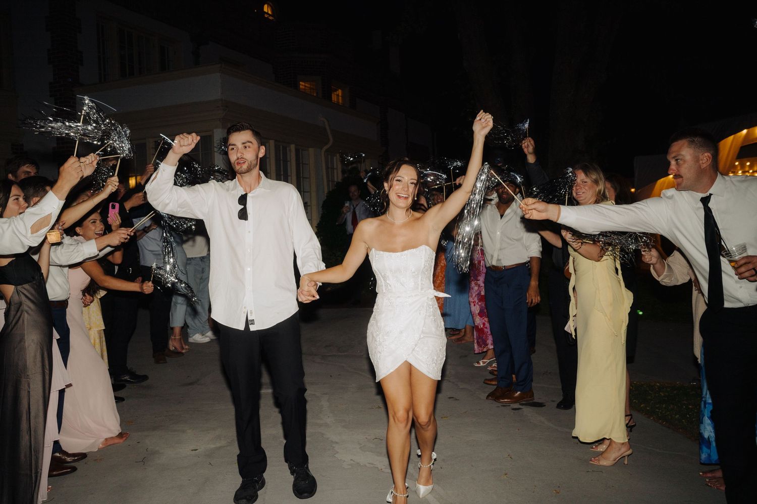 Wedding guests dancing and celebrating on a dark dance floor at night.