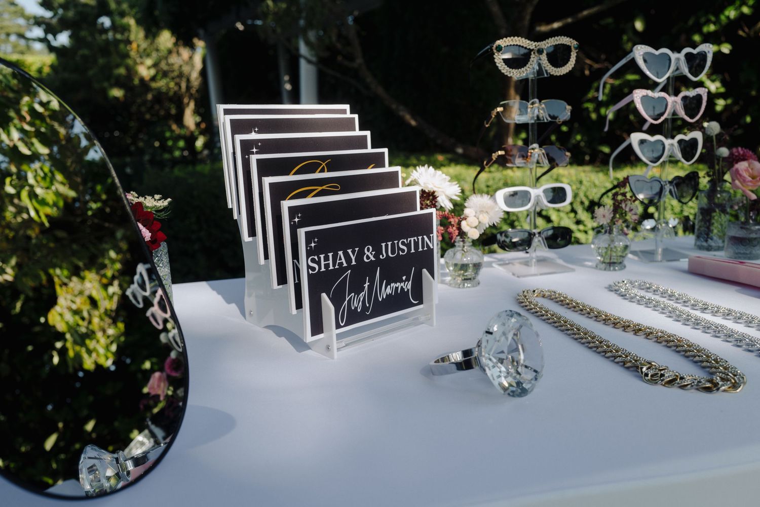 Wedding accessories display with sunglasses and guest books on a white table.
