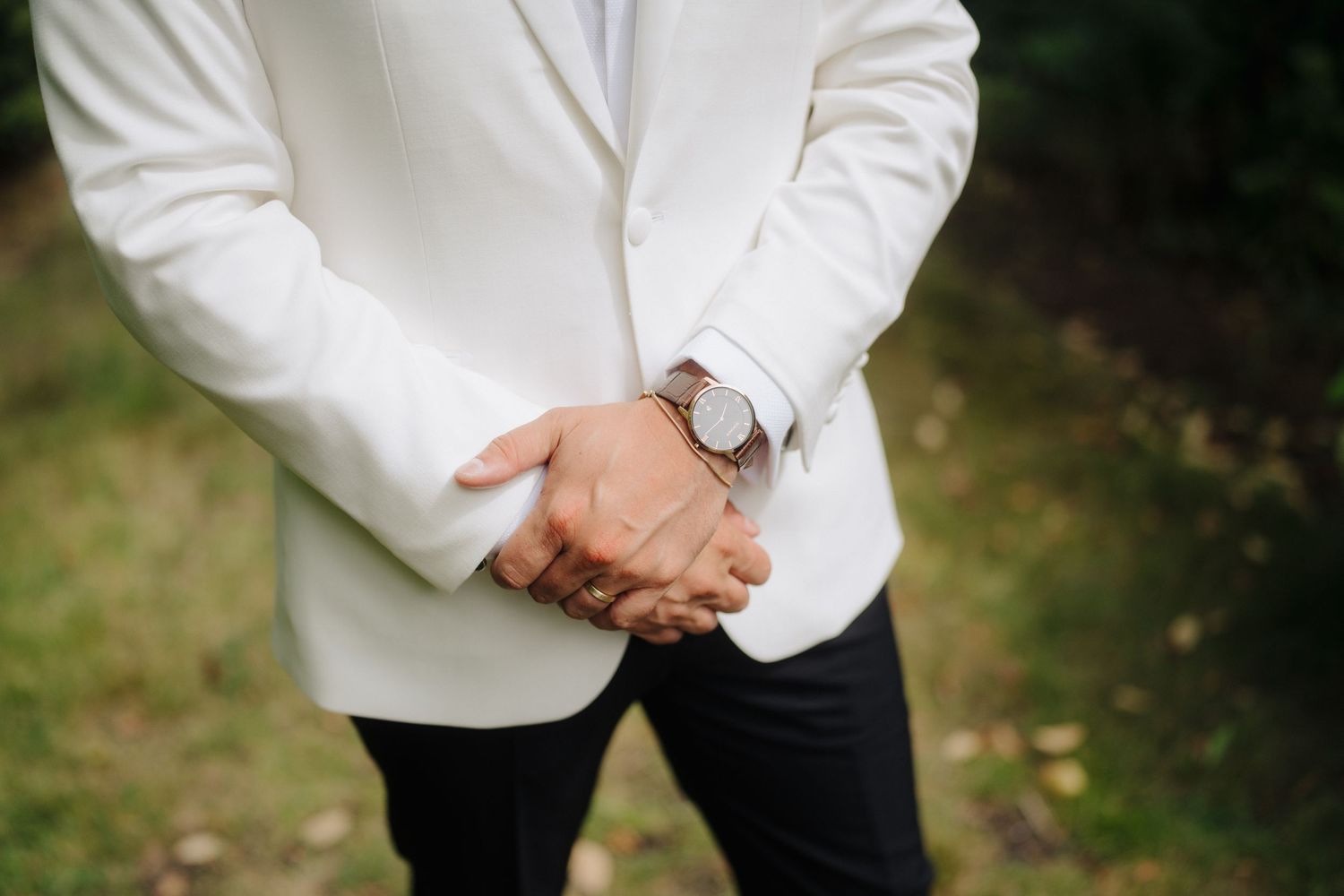 Detail shot of formal white tuxedo jackets at an elegant wedding.