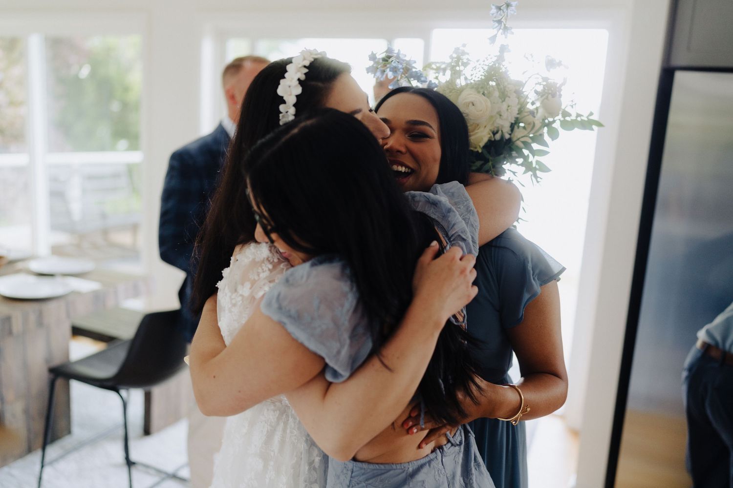 Wedding party sharing emotional embraces and hugs during an indoor celebration.