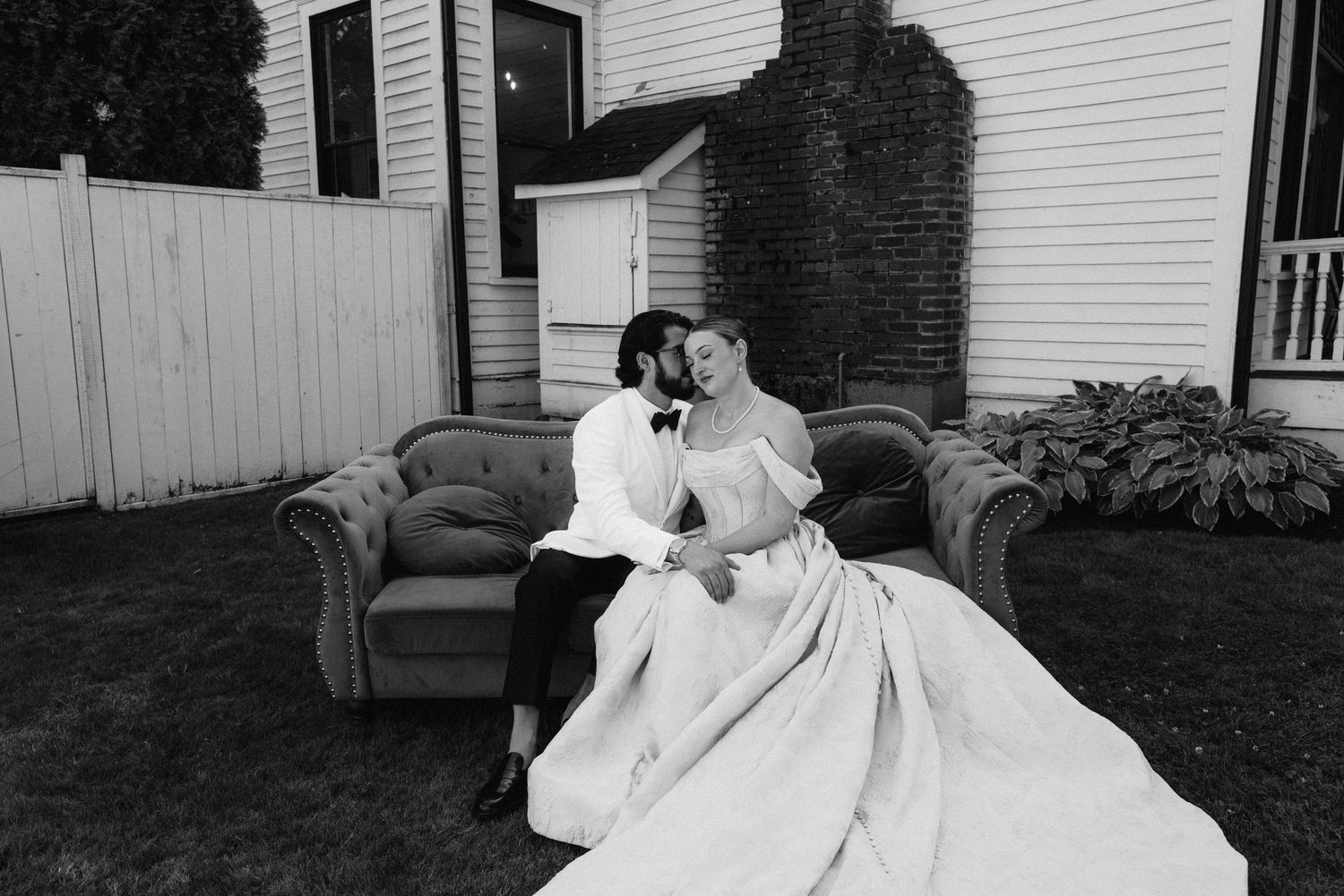 Classic black and white photo of wedding dress details against white house backdrop.