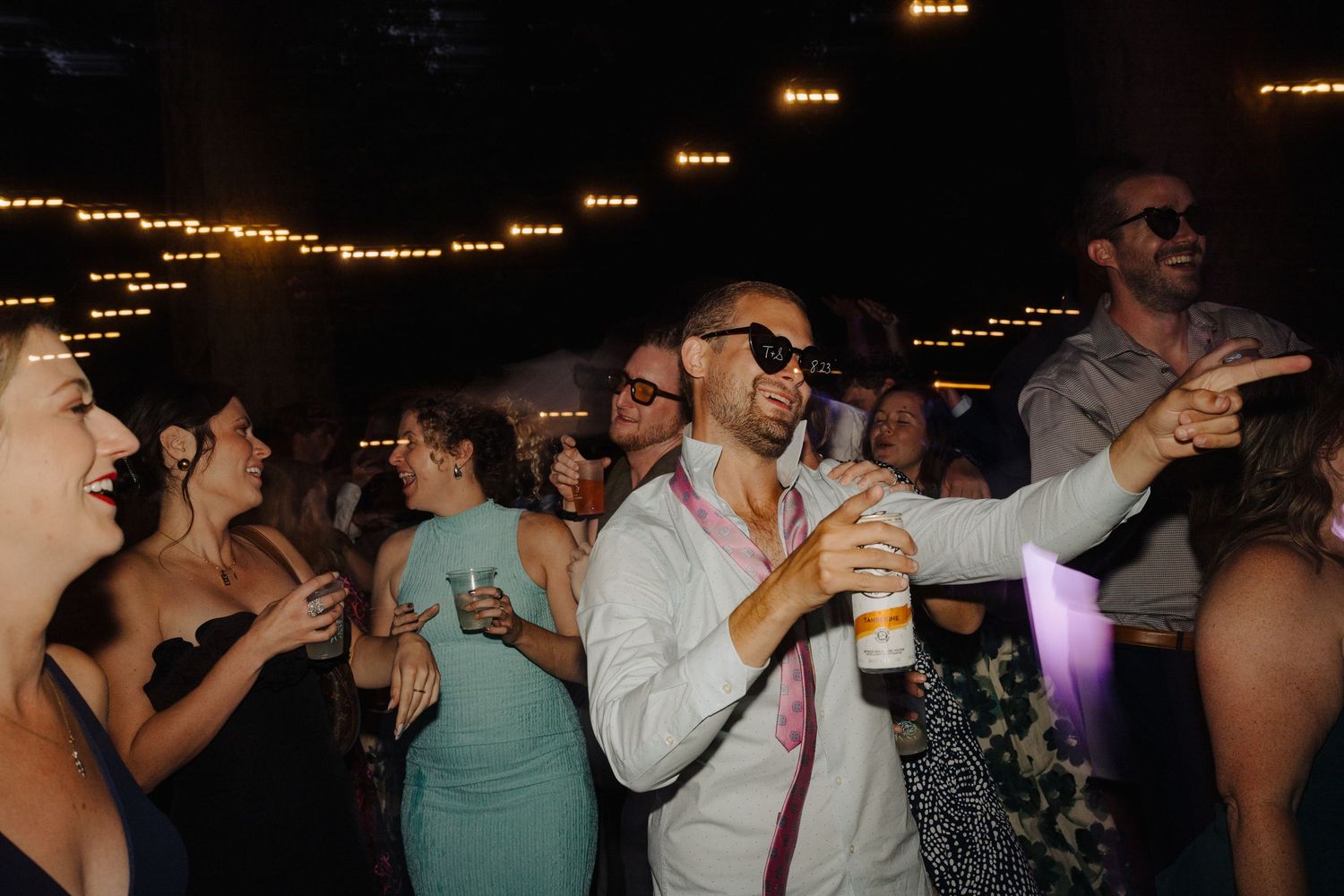 Wedding reception dance party with string lights creating a festive atmosphere.