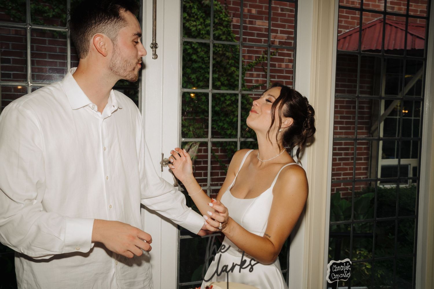 Candid moment of couple enjoying cake cutting ceremony at wedding reception.