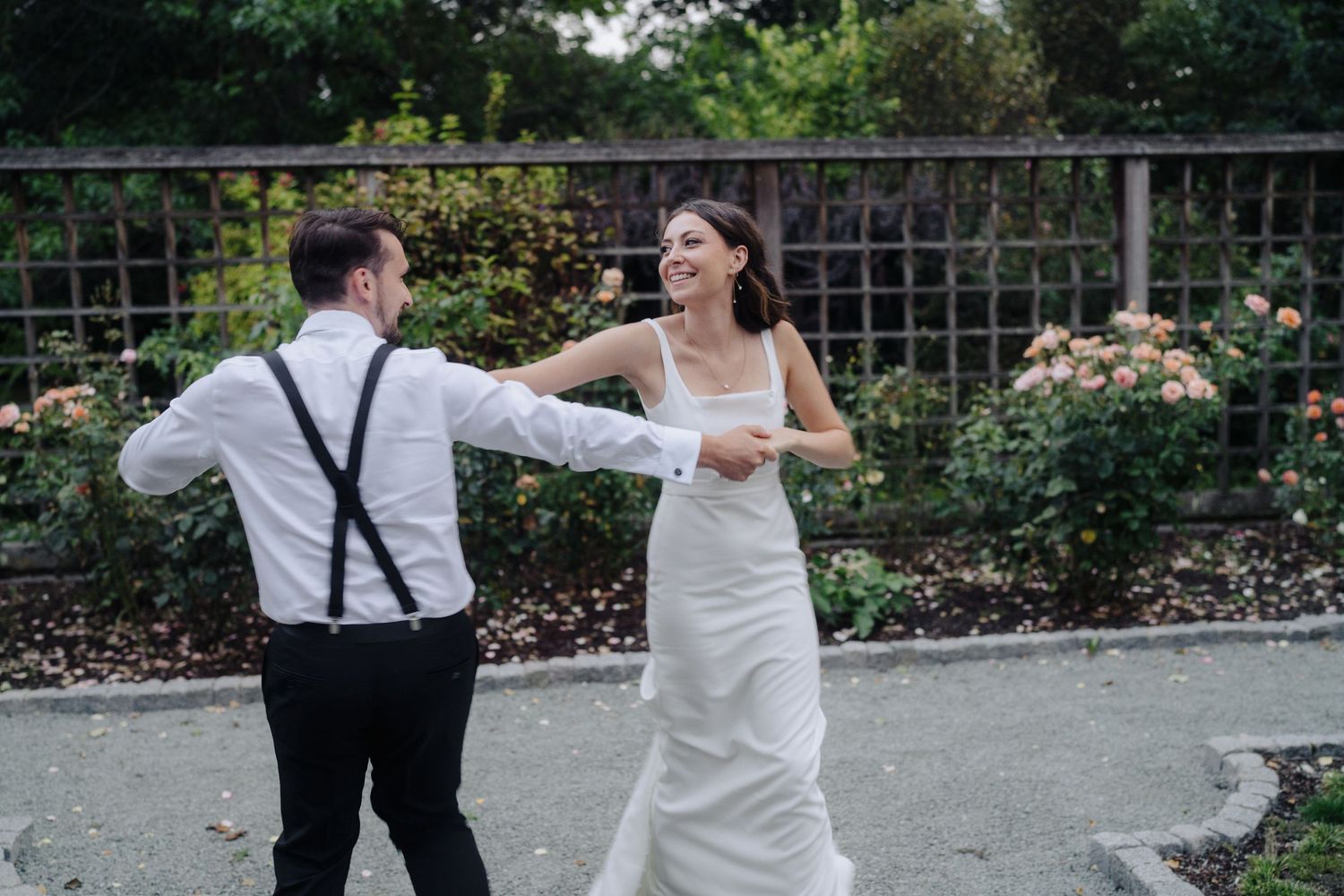 Candid wedding photo of couple walking through garden pathway.