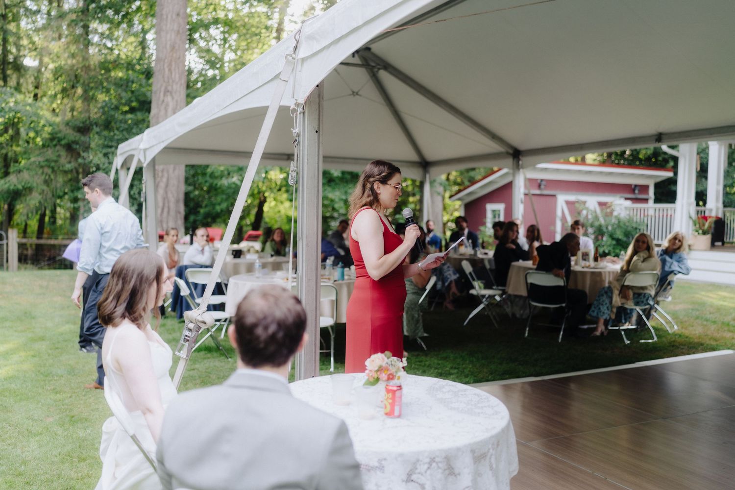 Wedding reception guests gathering under spacious white outdoor tent.