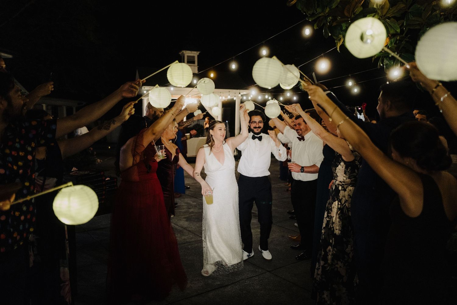 Evening wedding reception with paper lanterns creating romantic ambiance outdoors.