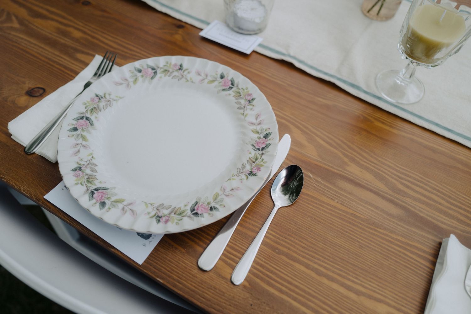 Empty elegant dinner plates with floral patterns set on a wooden table.