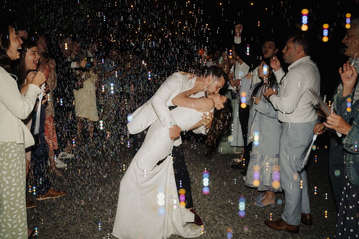 Wedding reception party with dancing guests under twinkling lights and confetti.
