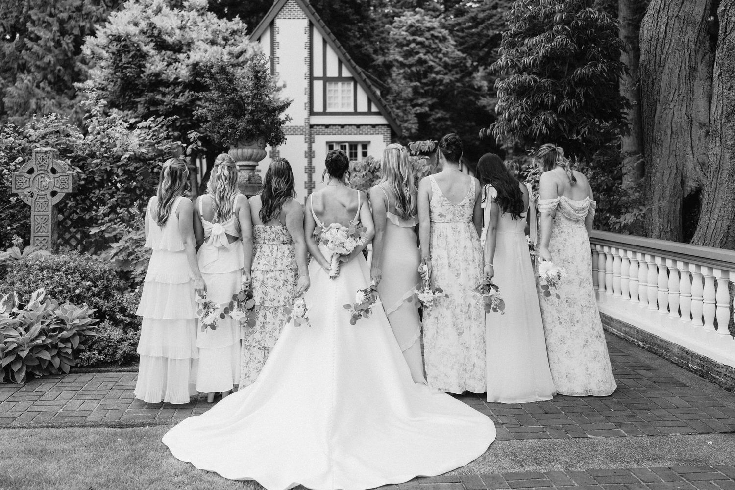 Wedding party in formal attire posing together outdoors for group photos.