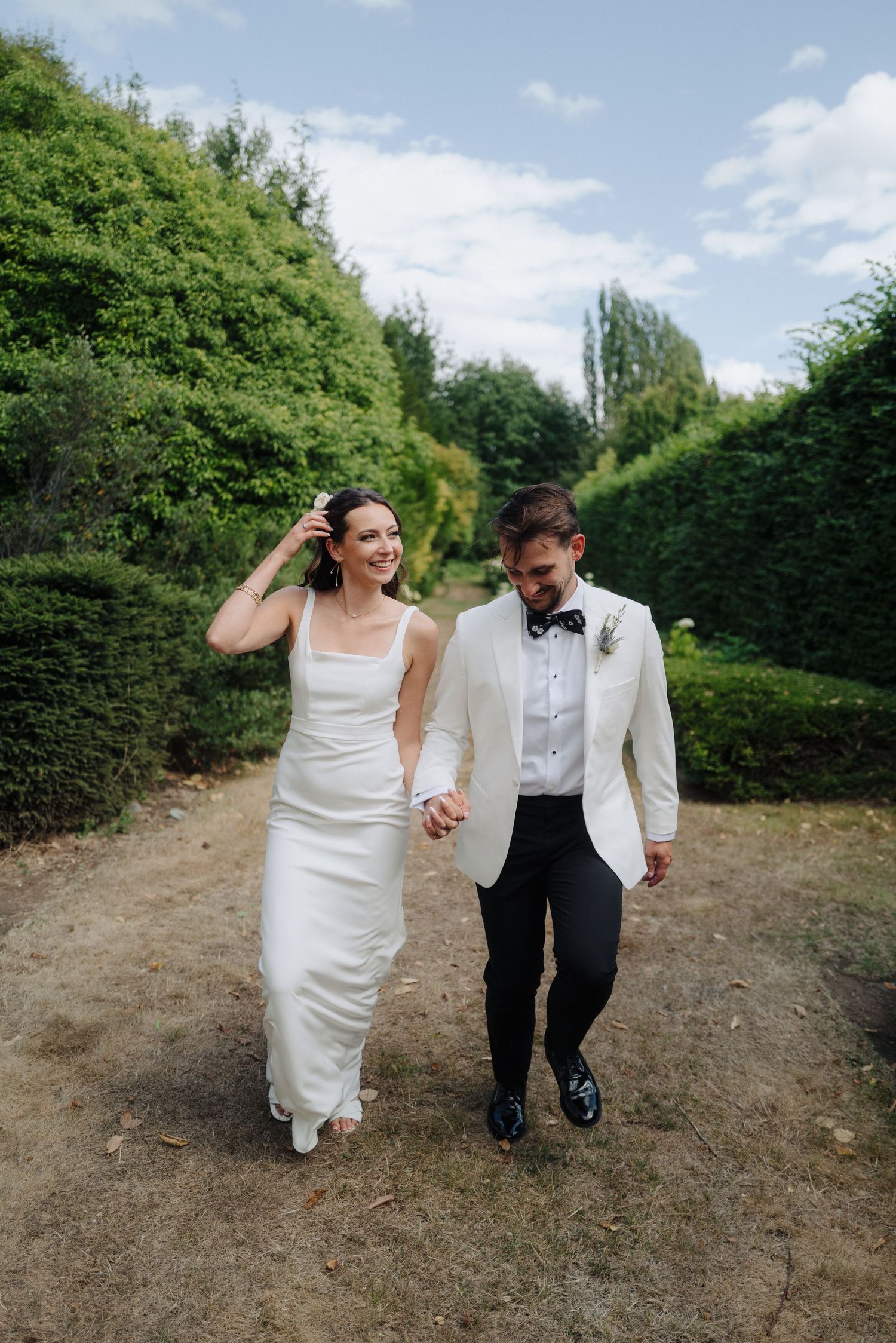 Newlyweds walk hand in hand through a scenic garden path on their wedding day.