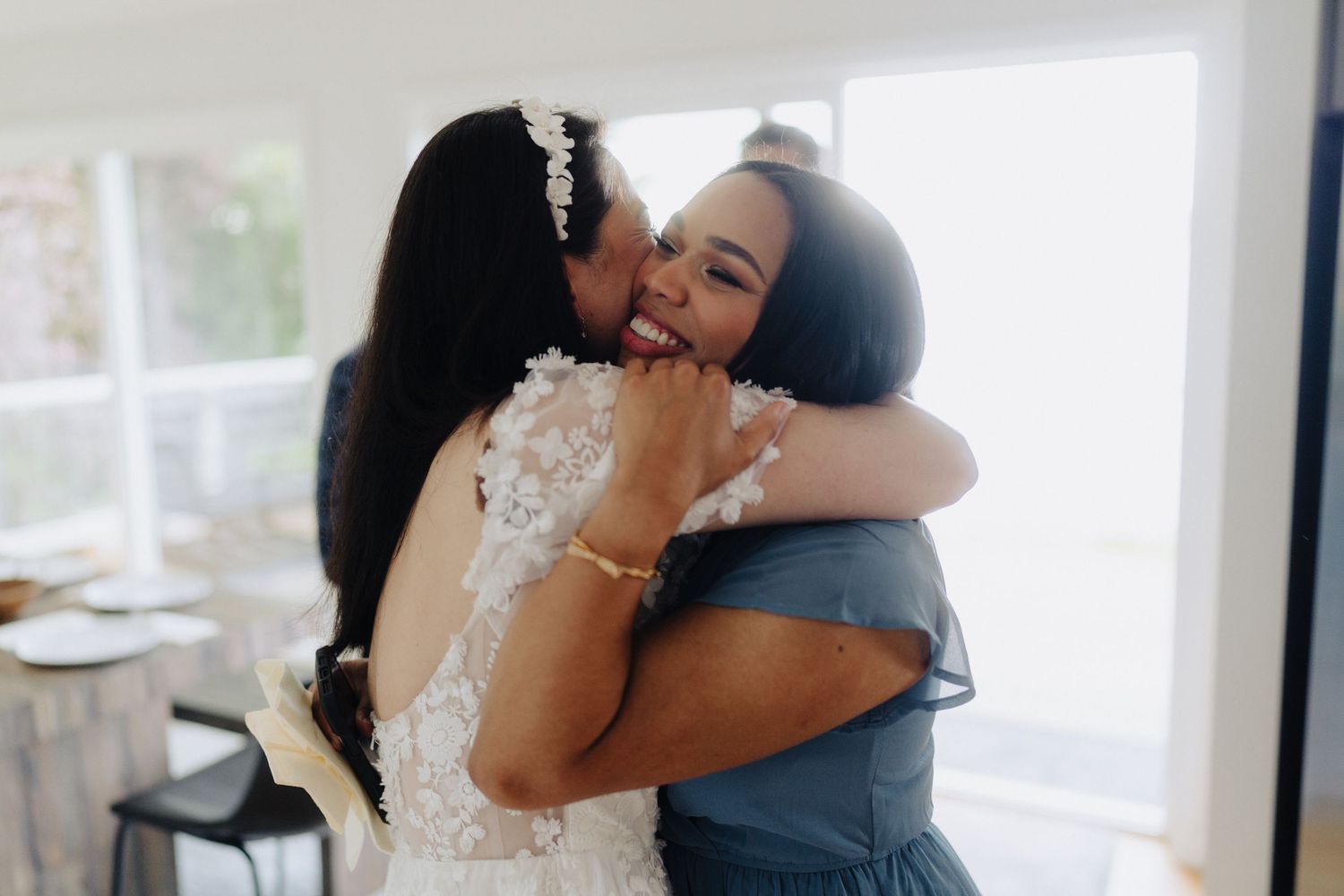 Emotional embrace shared during wedding celebration in bright indoor setting.