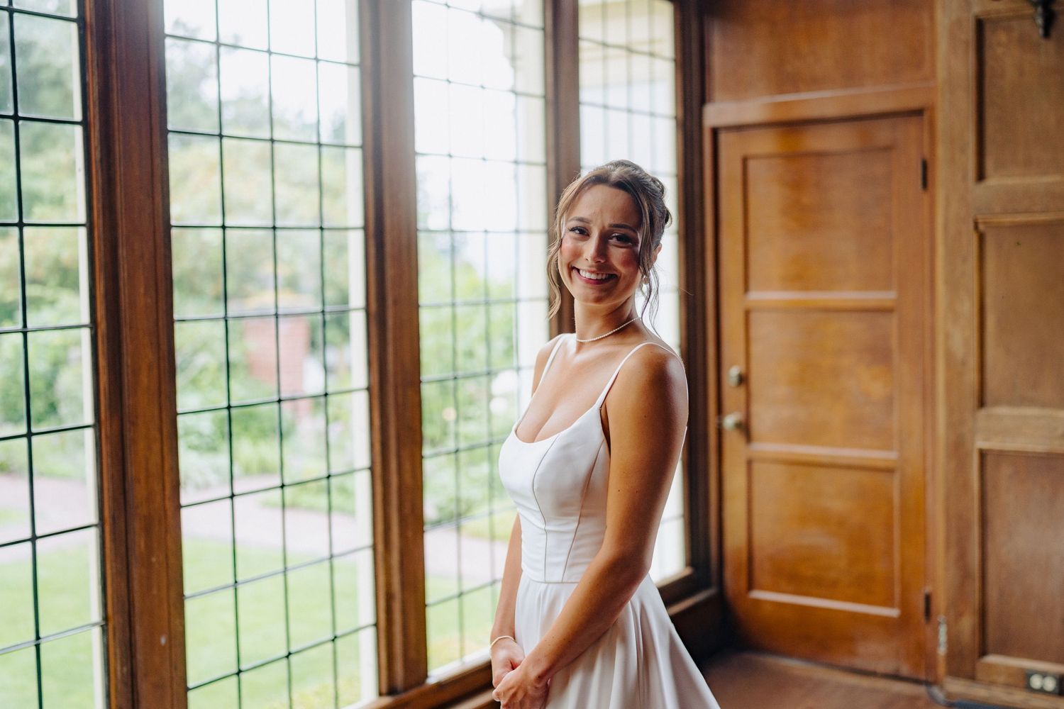 Sunlit bridal preparation room with large windows and wooden paneled walls.