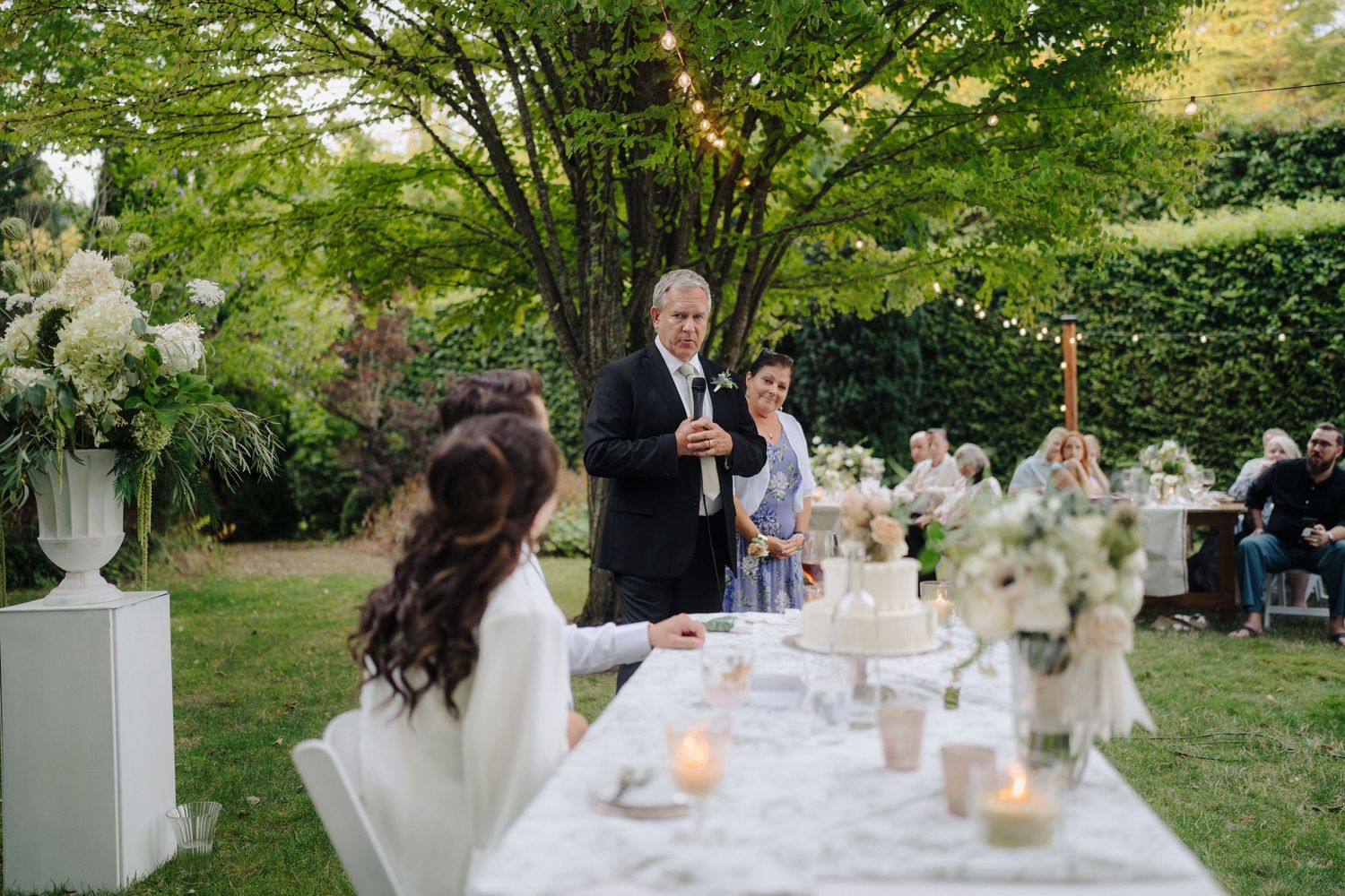 Outdoor wedding reception setup in garden with elegant table settings and natural decor.