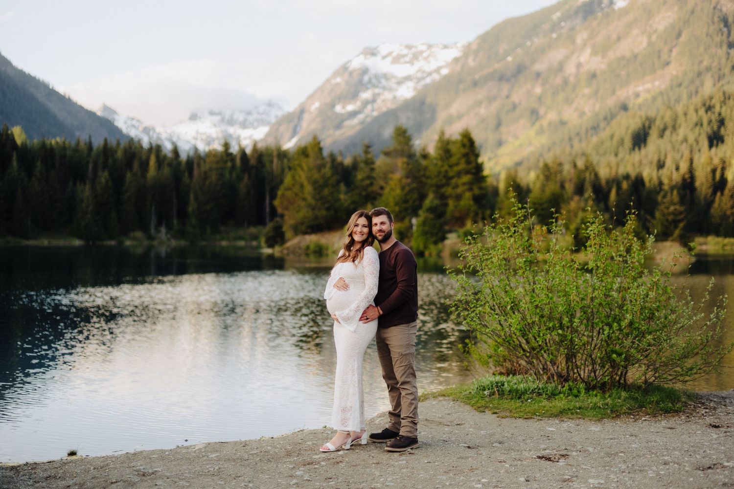 A maternity portrait with a stunning mountain lake landscape in the background.
