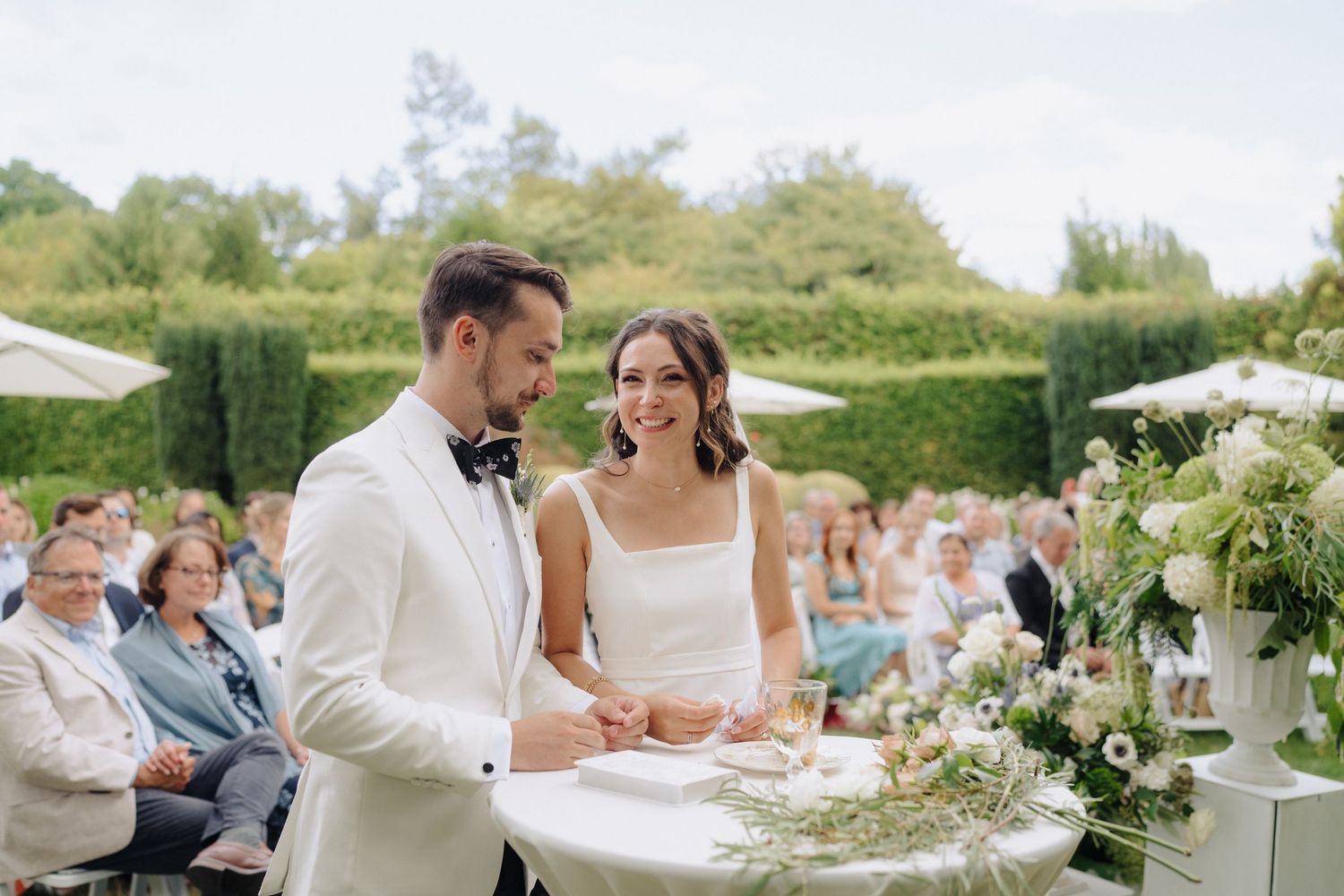 A beautiful garden wedding ceremony setup with white chairs and floral decorations.