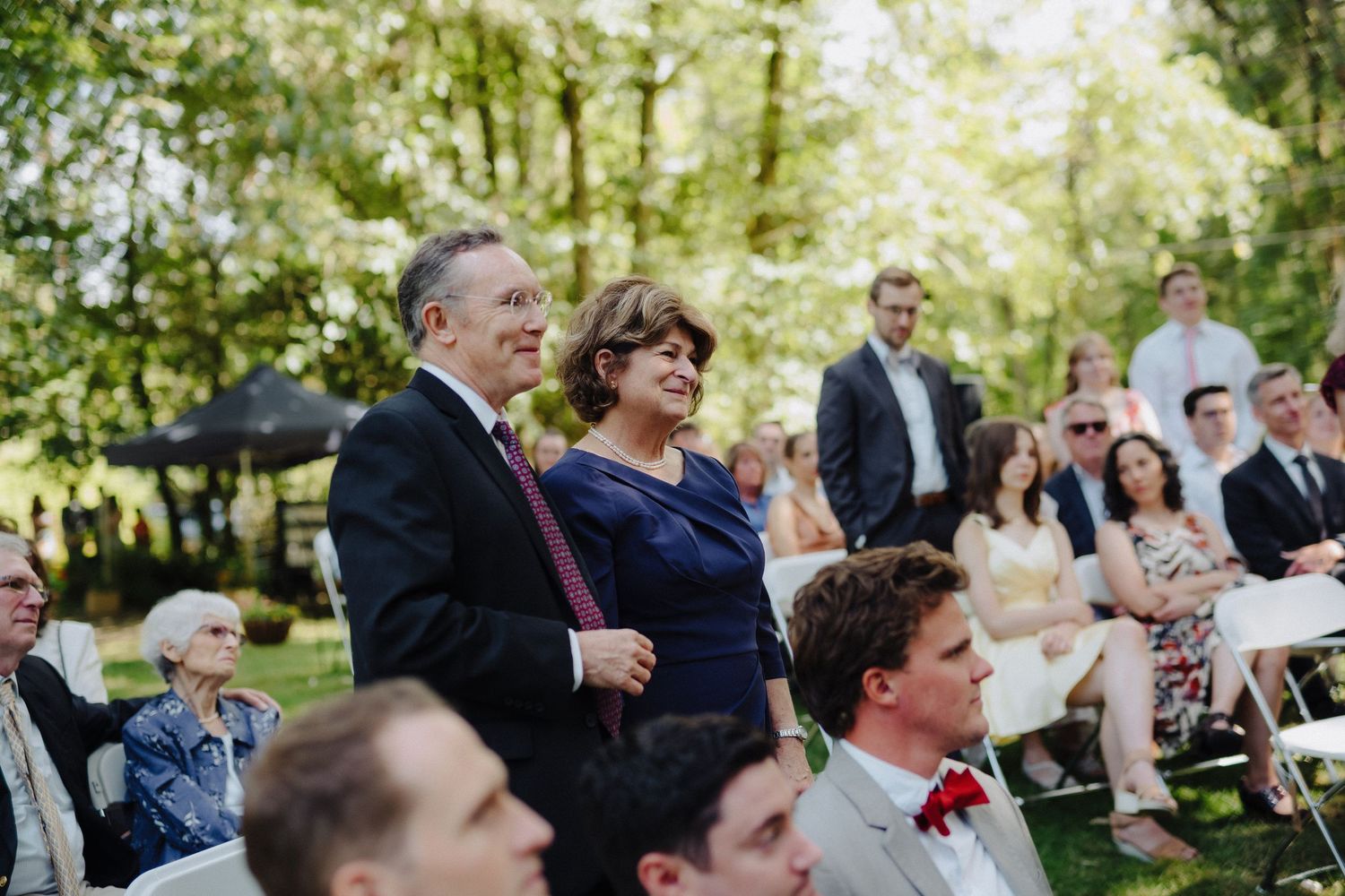 Wedding guests laughing and enjoying themselves during an outdoor garden ceremony.
