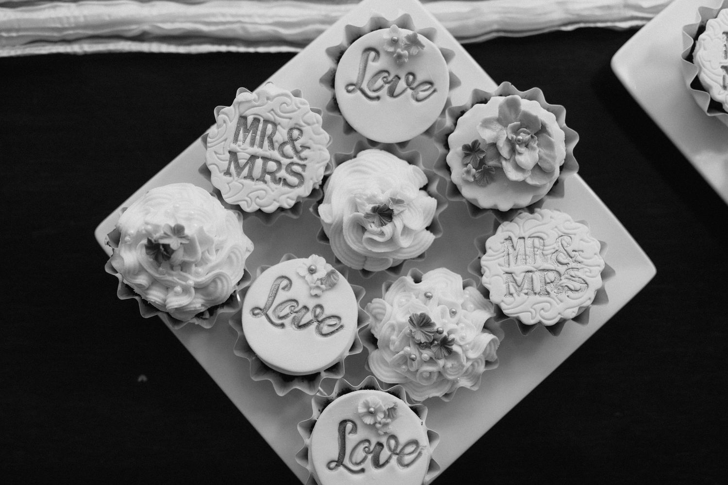 Black and white photo of decorated wedding cupcakes with 'Love' and 'Mr & Mrs' text.