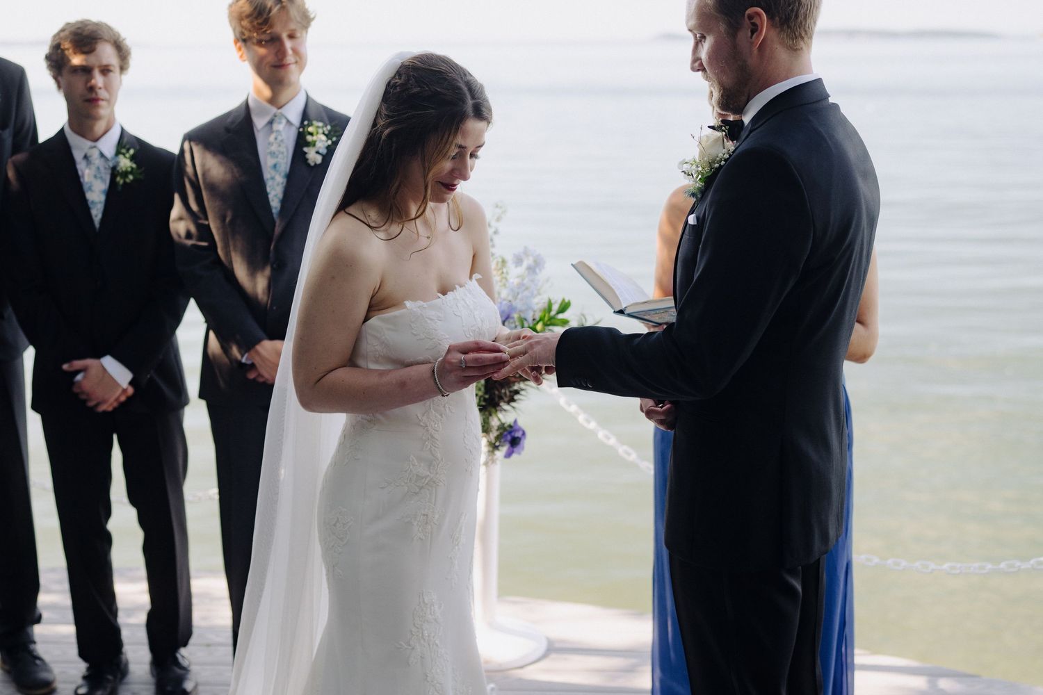 Exchange of vows during a waterfront ceremony with guests looking on.