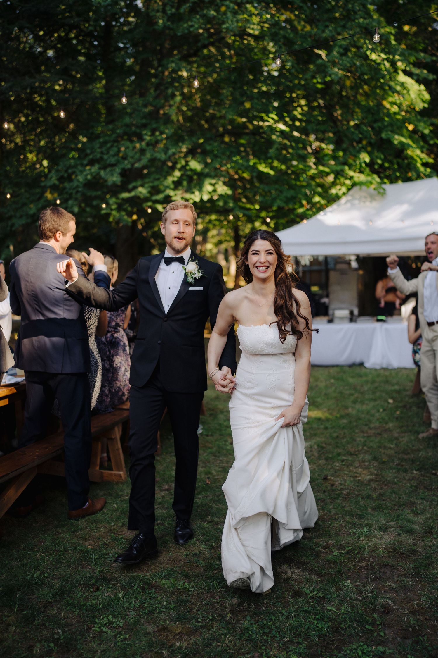 Wedding celebration in a garden setting with white tents and dancing guests.