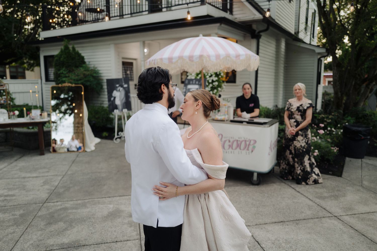 Outdoor wedding reception with white tent and guests celebrating on concrete patio.