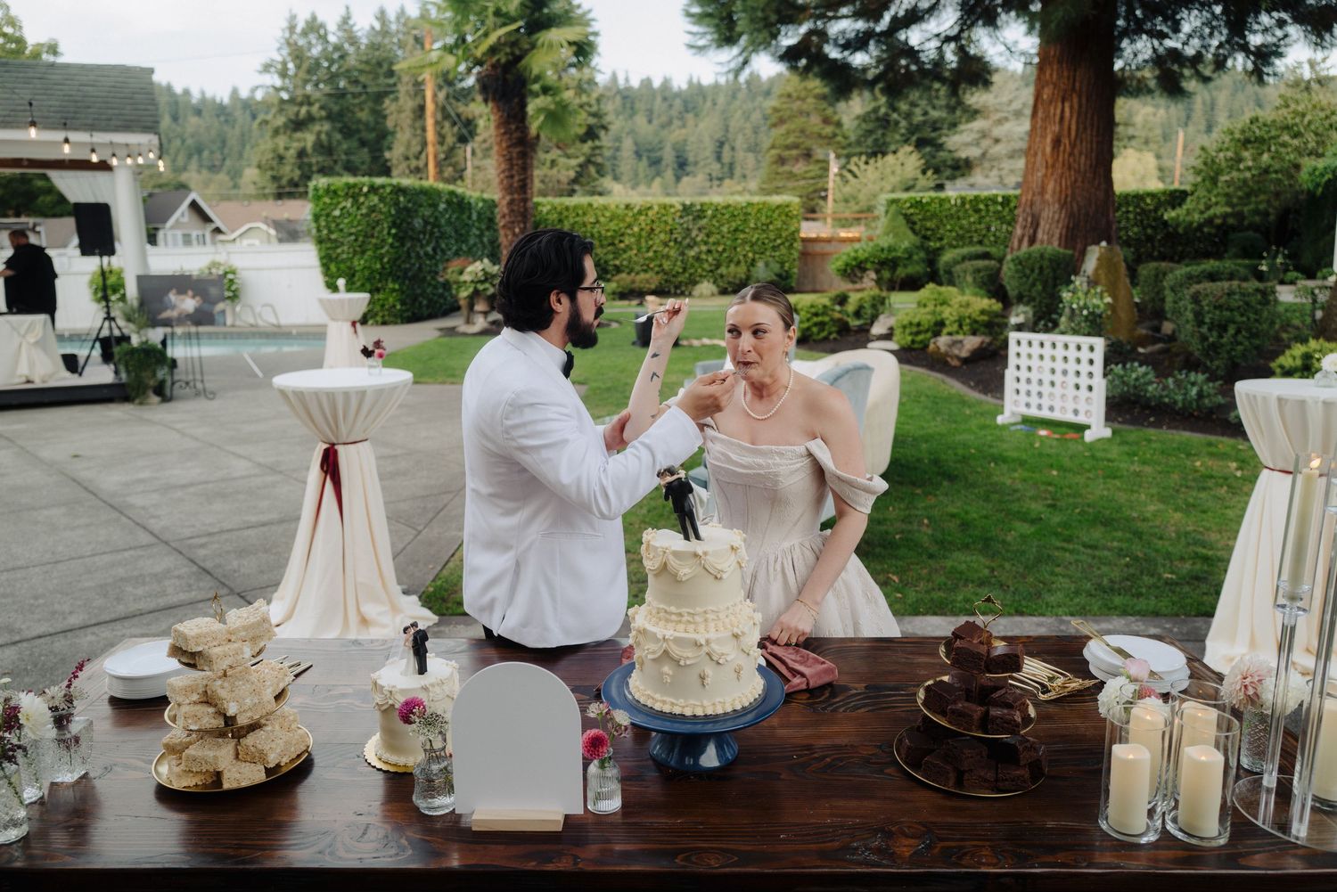 Wedding reception dessert table with rustic decor and lanterns at outdoor venue.