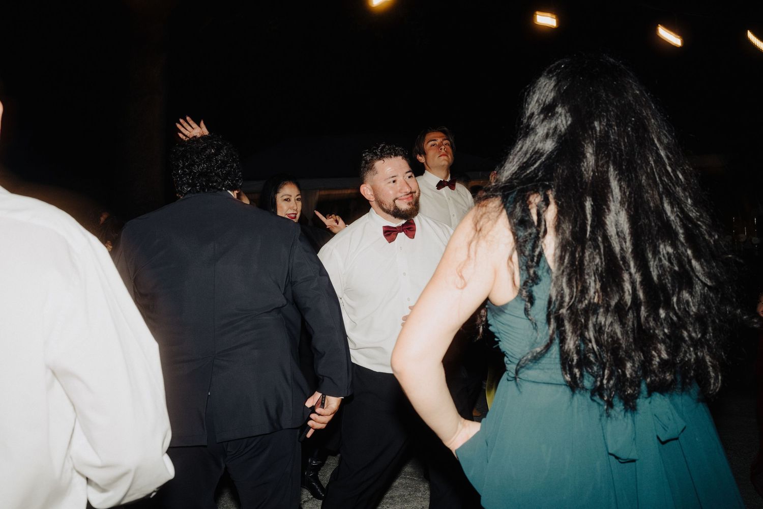 Wedding guests dance and celebrate at a lively evening reception.