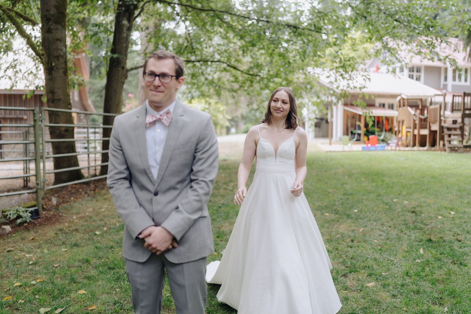 Wedding couple walking together on a green lawn surrounded by trees in a garden setting.
