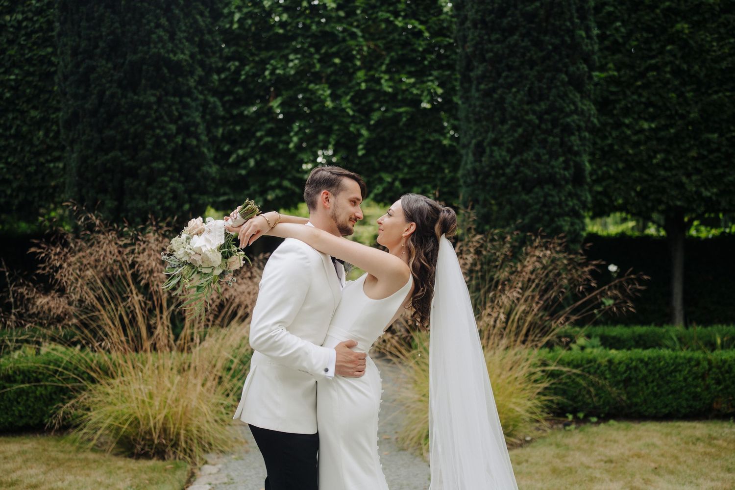 Wedding couple shares intimate moments in a verdant garden setting with natural greenery backdrop.