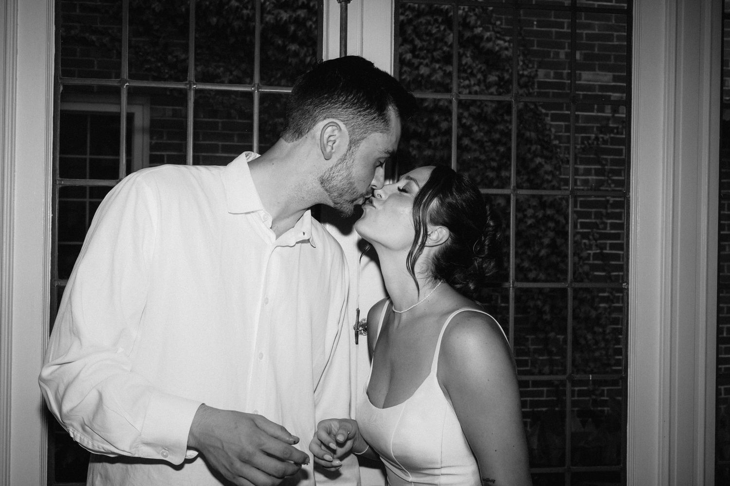 Black and white photo of newlyweds sharing an intimate moment during cake cutting.