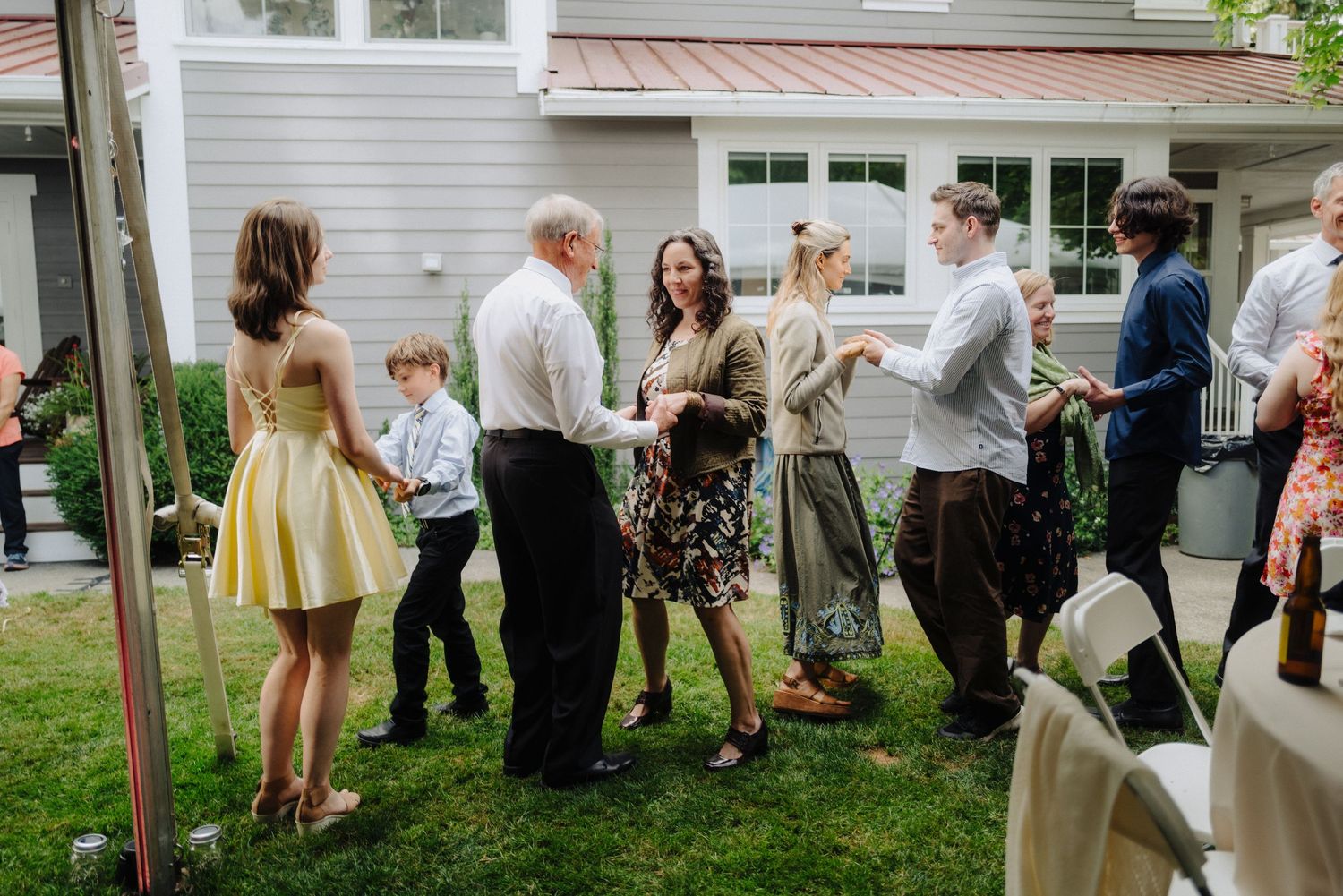 Wedding guests mingle and socialize on a lawn under a tent during the reception.