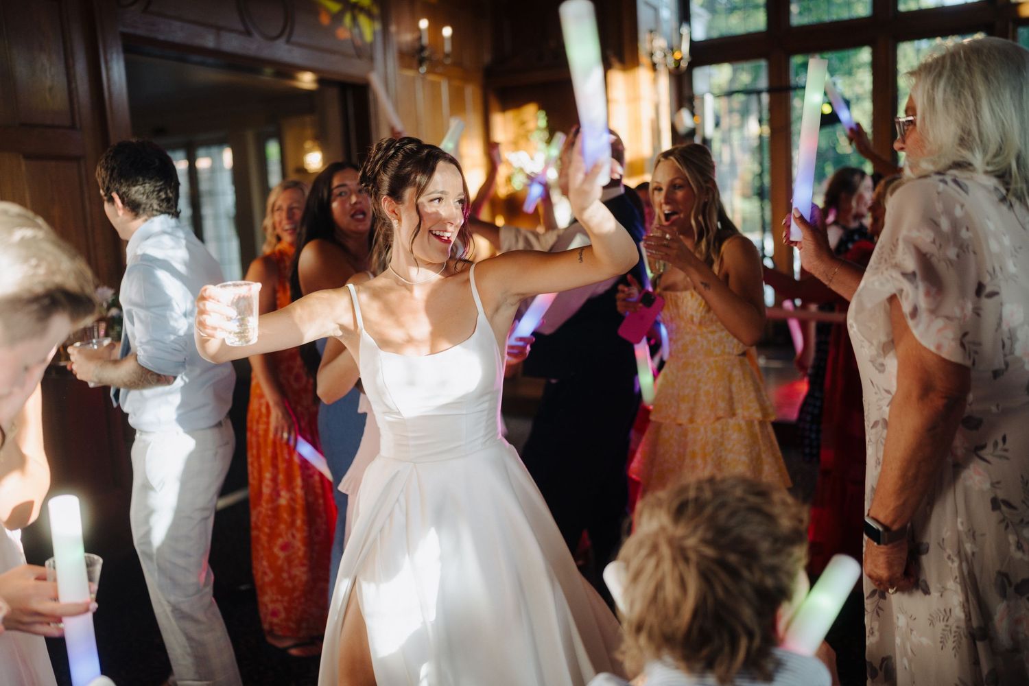 Wedding reception dance floor filled with guests celebrating under ambient lighting.