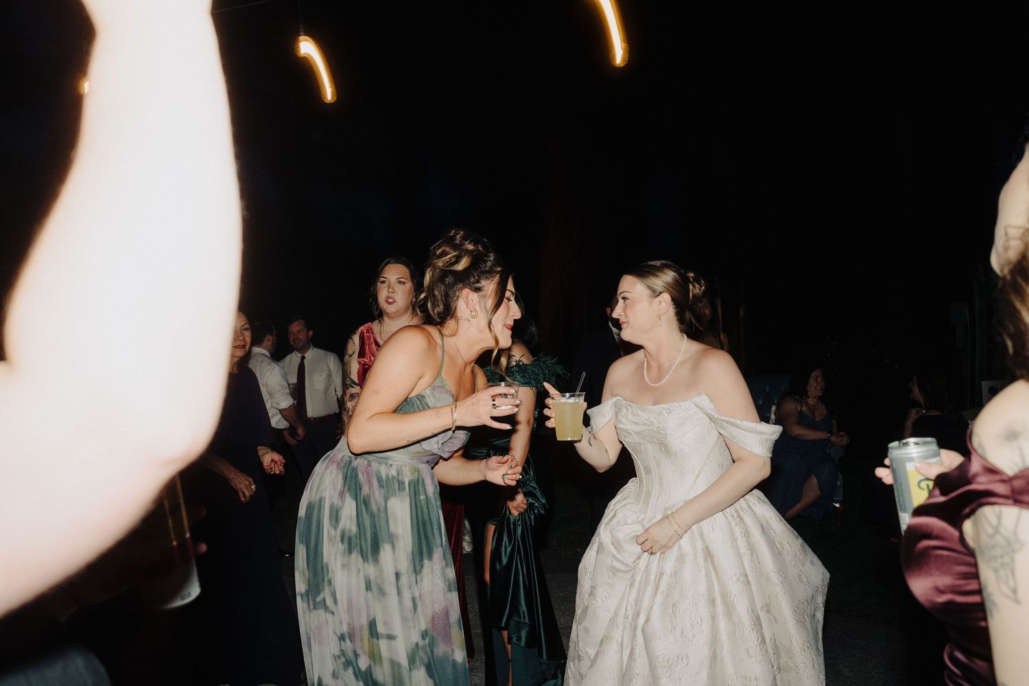 Evening wedding reception with string lights and guests mingling on dance floor.