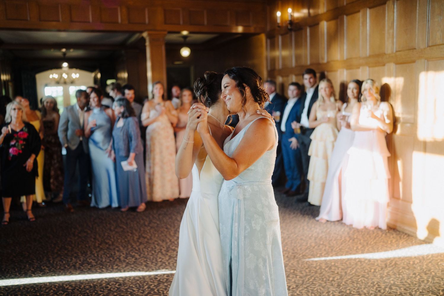 Wedding party in light blue dresses dancing during reception in an elegant ballroom.
