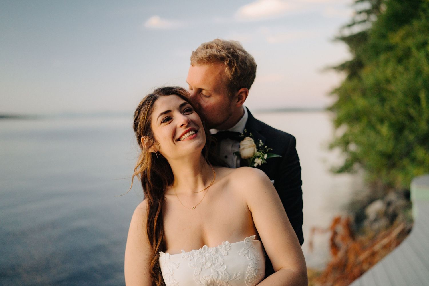 A couple shares an intimate moment against a scenic coastal backdrop during their wedding photoshoot.