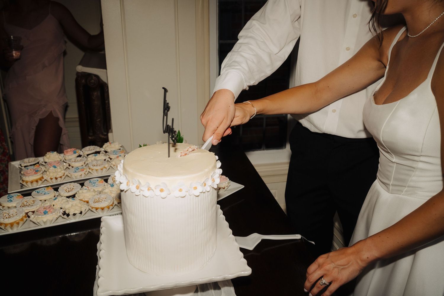 Close-up details of white wedding cake being cut during reception celebration.