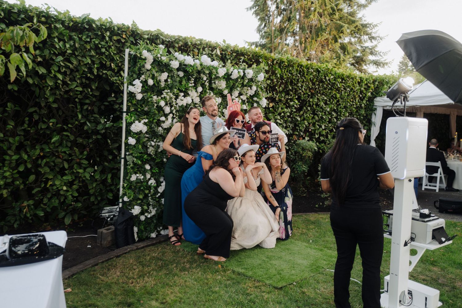 Wedding party celebrating outdoors with greenery and white decor.