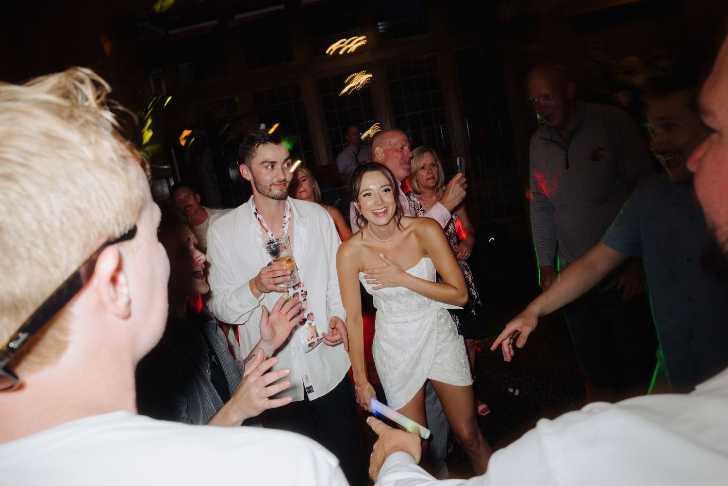 Wedding guests dancing and celebrating at a lively indoor reception party.