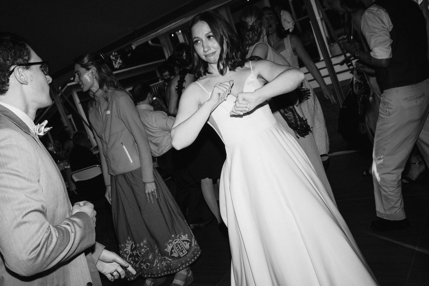 Wedding reception dance party under tent lighting with guests celebrating.