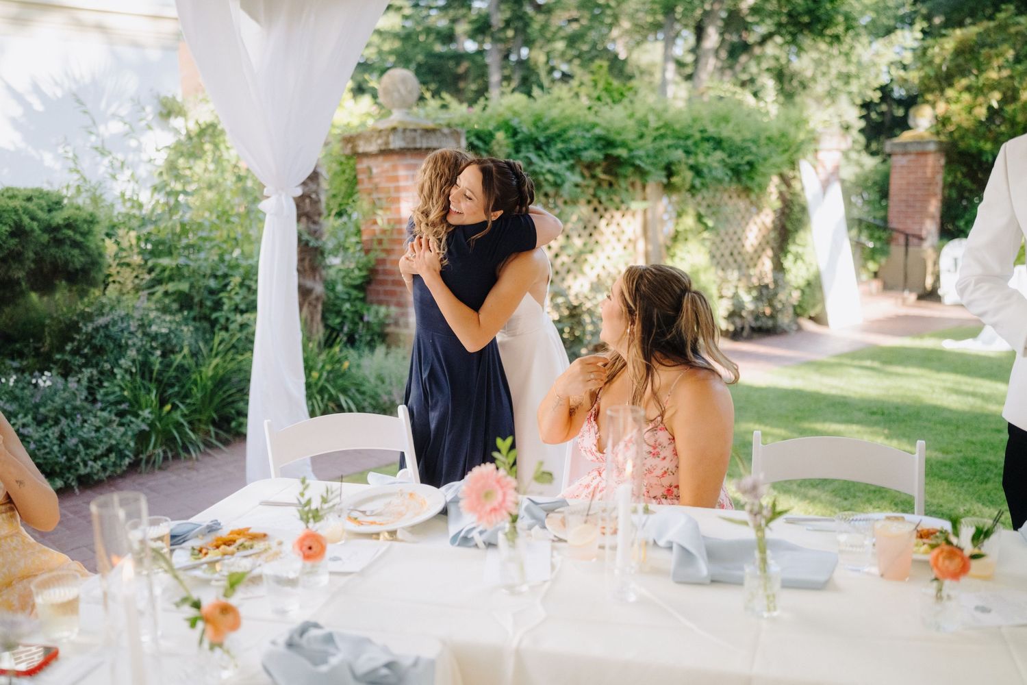 Wedding reception table settings outdoors with floral centerpieces and glassware.
