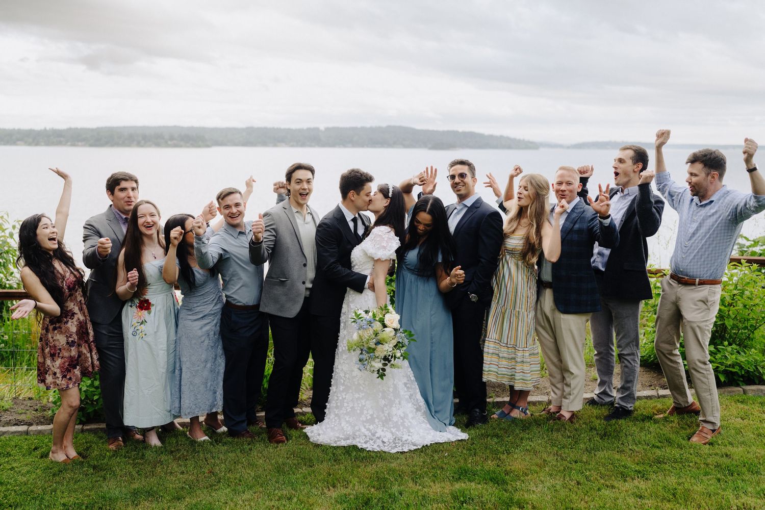 Wedding party posing for fun group photos on a grassy hillside with dramatic poses.