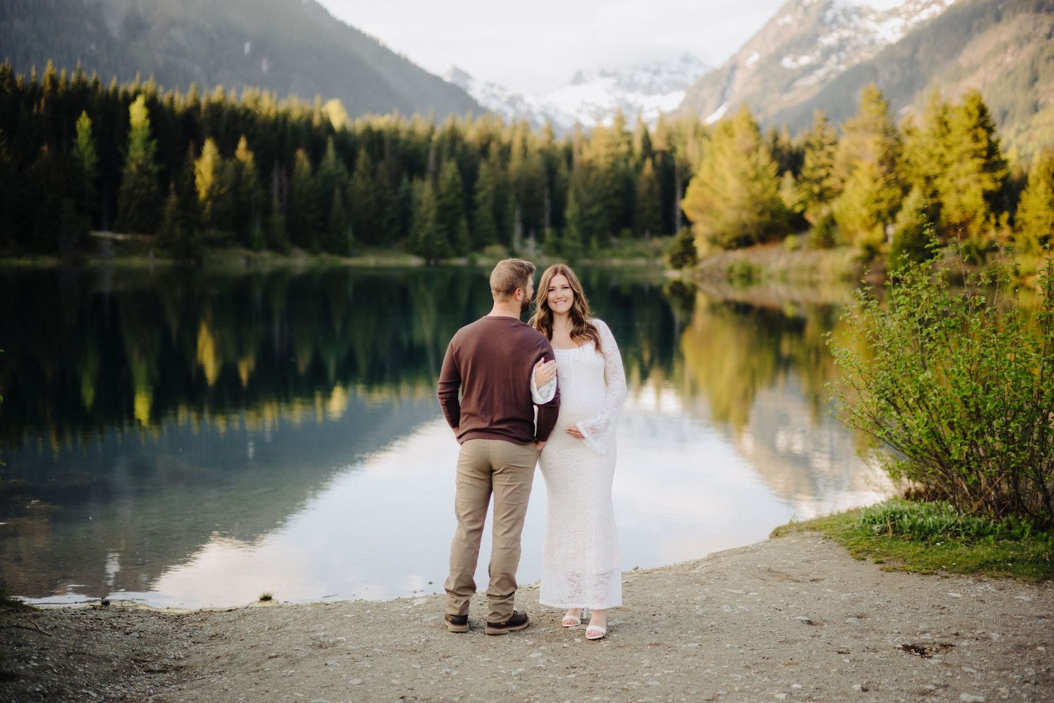 Couple enjoys romantic moment by scenic mountain lake surrounded by autumn colors and evergreen trees.