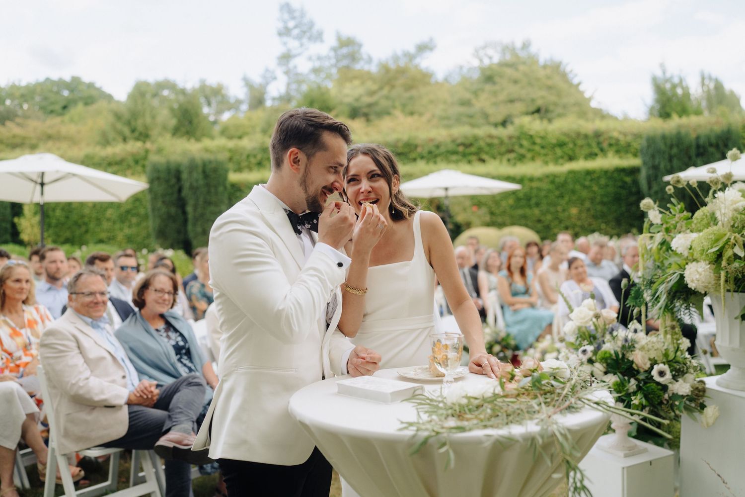 Wedding reception celebration with guests dining at decorated tables in an outdoor garden setting.