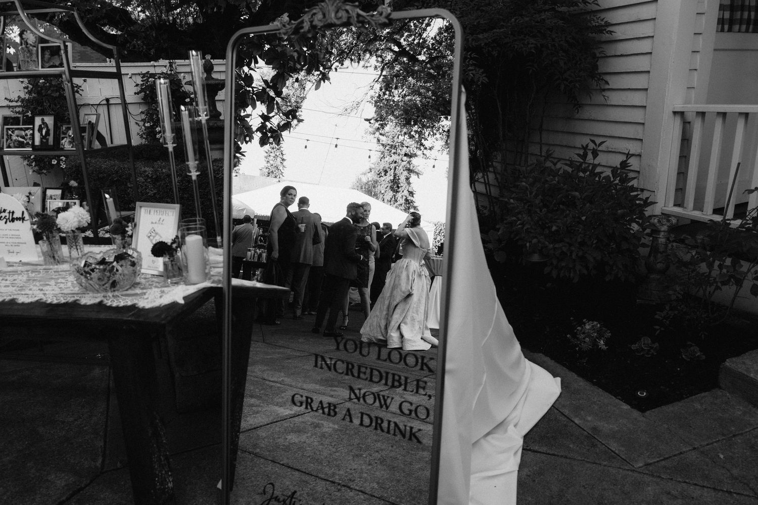 Black and white photo of wedding celebration with guests outside a traditional venue.